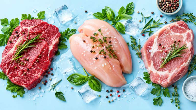 Сырое мясо и курица со льдом на синем фоне